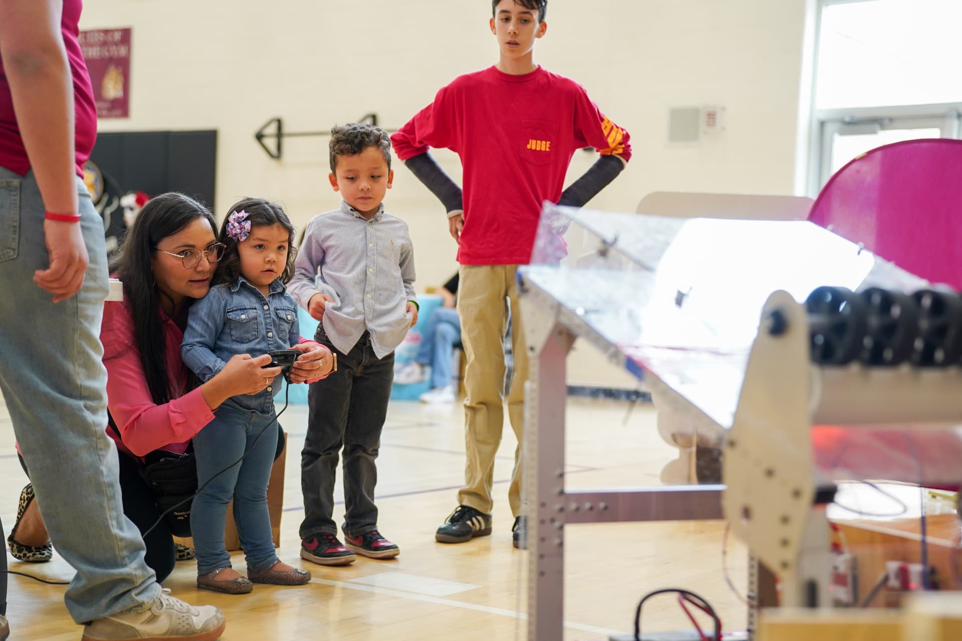 Familias y estudiantes operando un robot en Triunfa en Tecnología, Glendale Middle School